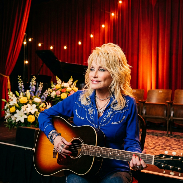 Dolly Parton holding a guitar beneath a banner reading A TRIBUTE TO A LEGEND DOLLY PARTON (1946 - 2024).